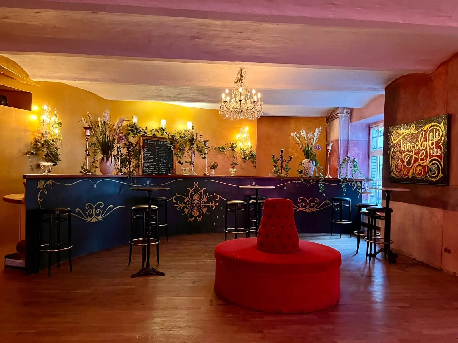 Die Bar im Tangoloft mit Kronleuchter, Blumen und rundem roten Sofa